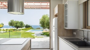 A modern kitchen with a view of a pool and garden. - Luria Homes (Sithonia)