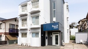 A multi-story hotel with a 'Stay Airport' sign, balconies, and a gated entrance. - Stay Airport (Fukuoka)