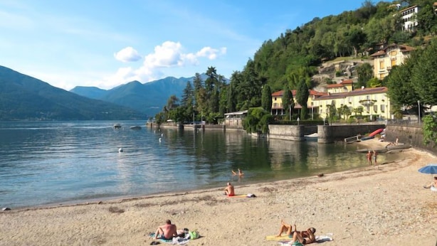 A beach with people sunbathing and swimming, surrounded by houses and mountains. - Angelina by Interhome (Luino)