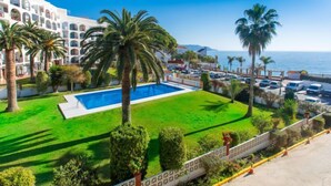 Ein Hotel mit Pool, Palmen und Meerblick.
