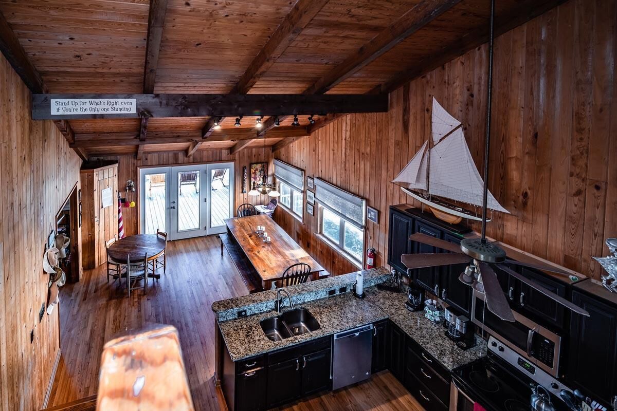 A wooden cabin interior with a kitchen, dining area, and a sailboat model.