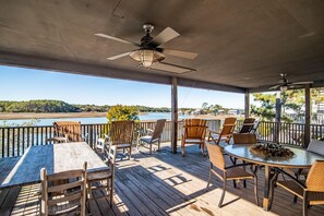Enjoy a serene view of the water from this outdoor deck, complete with comfortable seating and a ceiling fan.