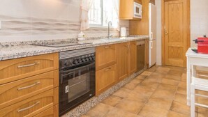 Een keuken met houten kasten, een inbouwoven, een magnetron en een koelkast.