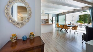 A modern dining area with a wooden table, chairs, and a large mirror on the wall. - Pool villa in Castelmola, Taormina, Sicily (Castelmola)