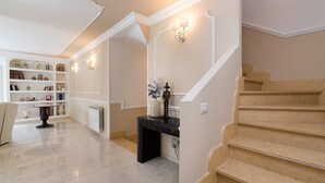 A spacious hallway with a marble floor, a black console table, a white radiator, and a staircase with beige steps. - Pool villa in Castelmola, Taormina, Sicily (Castelmola)