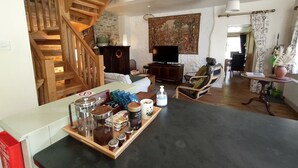 Un salon chaleureux avec un escalier en bois, un téléviseur à écran plat, une table basse avec des collations et une bibliothèque.