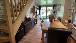Un espace repas comprenant une table en bois, des chaises et un escalier.