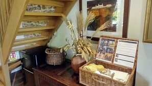 Un escalier en bois, un tableau encadré, un panier en osier et un vase contenant des plantes séchées.