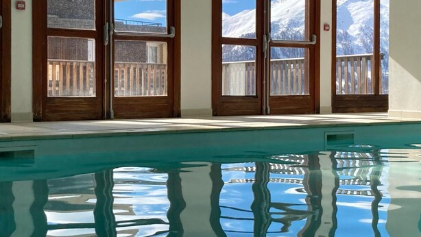 A pool with clear reflections, large windows with wooden frames, and a view of snow-capped mountains. - 2-room cabin apartment, 6 people, pool, parking, WiFi (Orcières Merlette)