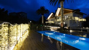 A modern two-story house with a swimming pool, surrounded by palm trees and string lights. - Villa Carmen by Basquelidays (Hondarribia)