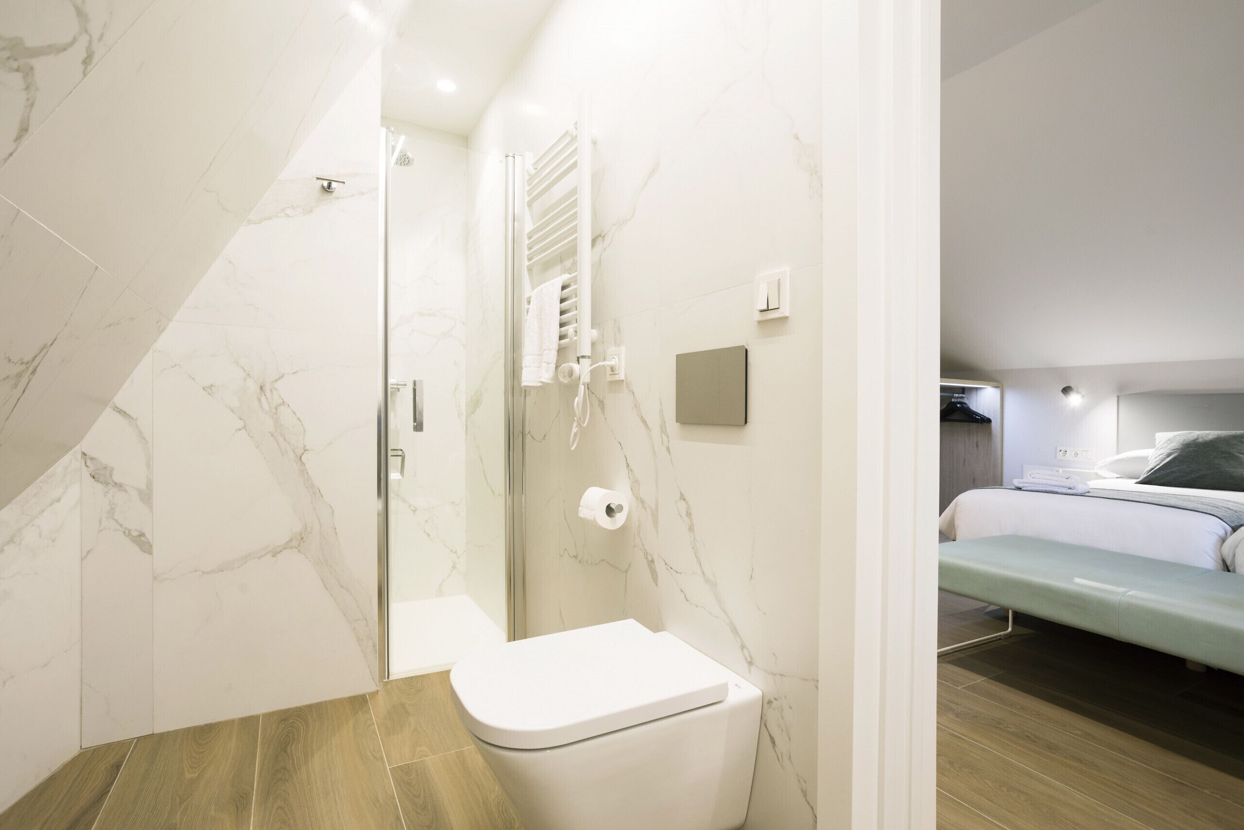 Un baño moderno con pared de mármol, ducha e inodoro.