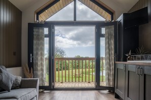 Ein Zimmer mit einer großen Glasschiebetür, die auf einen Balkon mit Holzdeck und einem Picknicktisch führt.