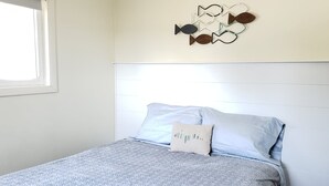 Een slaapkamer met een bed, kussens en een kunstwerk aan de muur.