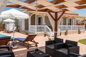 A poolside area with lounge chairs, umbrellas, and a covered patio. - Blossom Villa (Zakynthos)