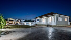 A spacious outdoor area with a paved walkway leading to a building with a tiled roof and white walls. - Blossom Villa (Zakynthos)