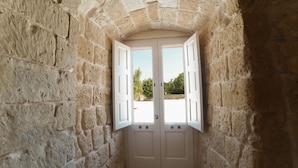 A stone-walled room with a double door and a small window.