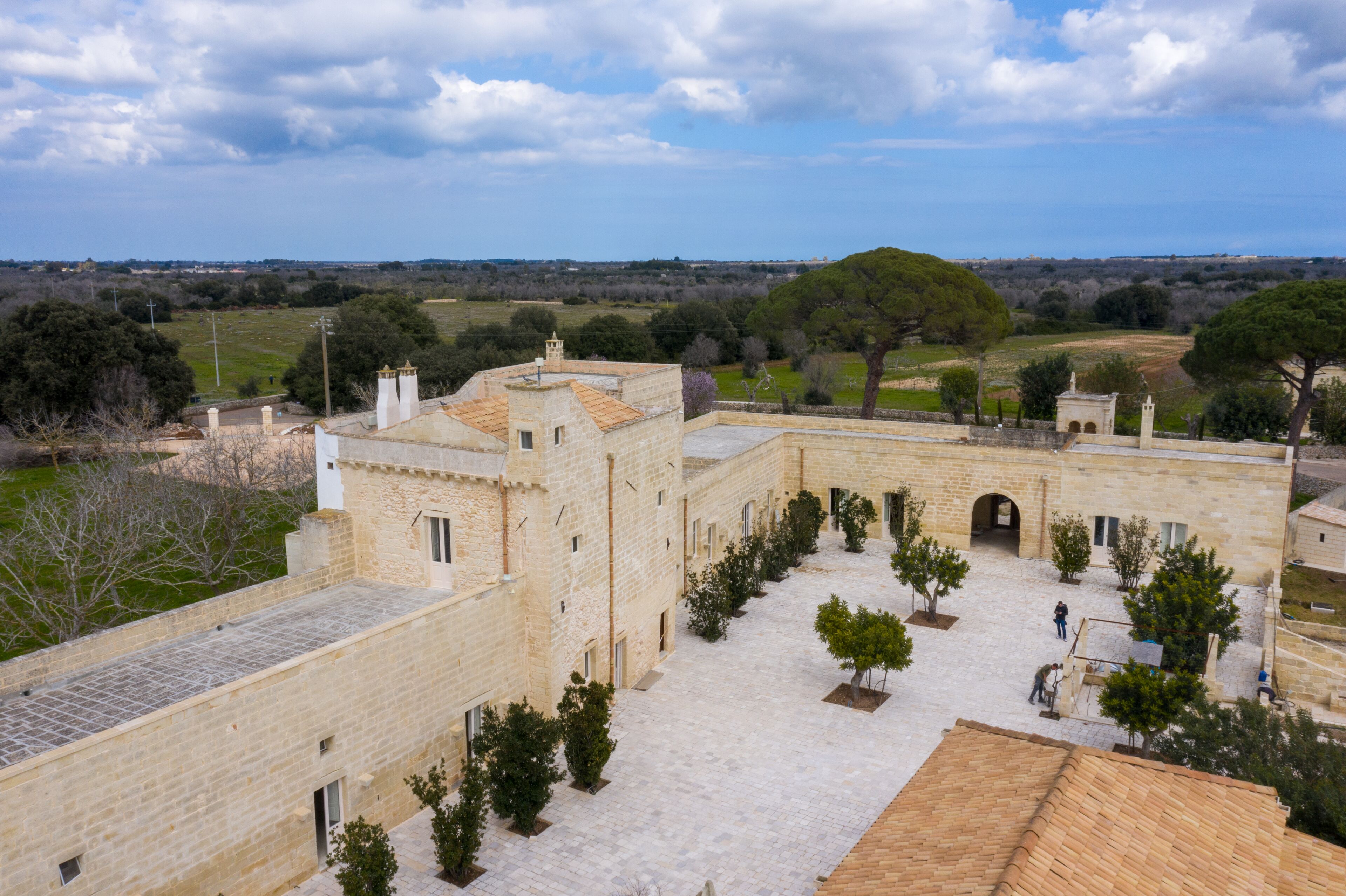 A courtyard with stone buildings, a paved area, and trees.