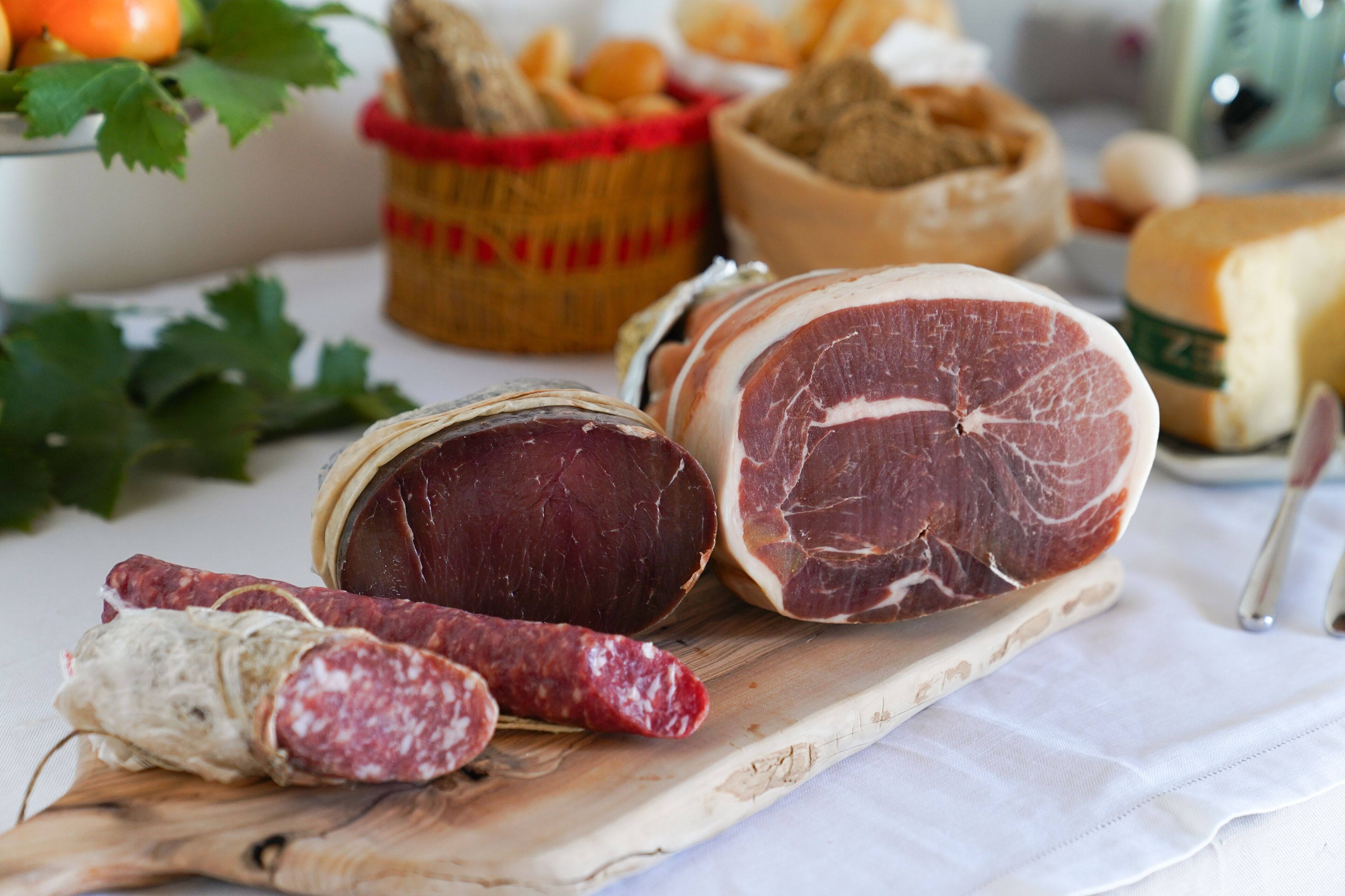 A variety of cured meats and cheeses on a wooden board.