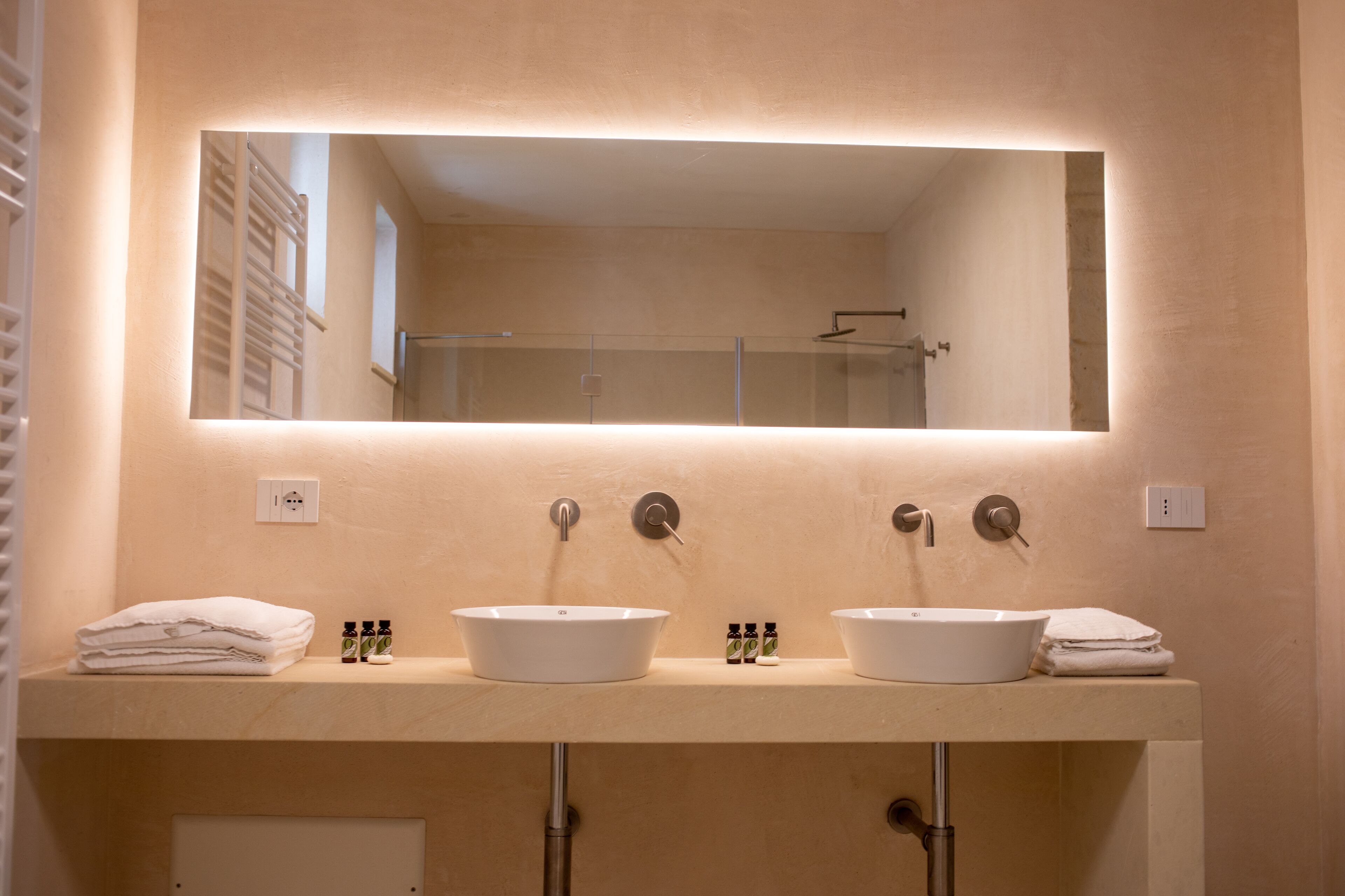 Un baño con dos lavamanos, un espejo grande y un perchero para toallas.