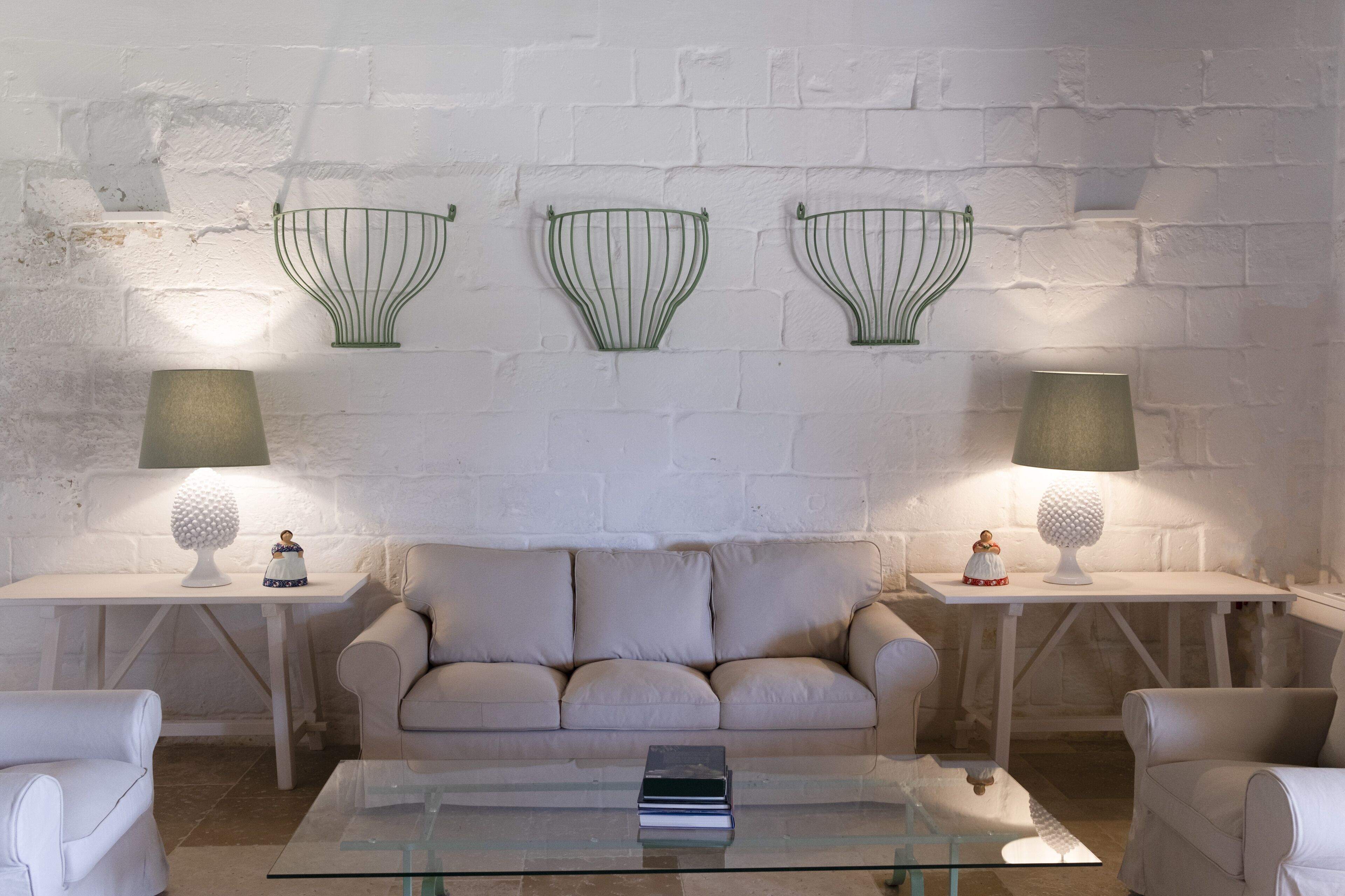 A living room with a beige sofa, two white side tables with lamps, and decorative wall sconces.