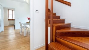 A wooden staircase leading to a second floor, a dining area with a table and chairs, and a window with natural light. - GuestHost - The property enjoys a strategic position, just a few steps from the historic center and only 10 minutes by car from the hospital. Its location makes the apartment perfect for any type of trip: nearby, you can find typical bars, ethnic restaur (Udine)