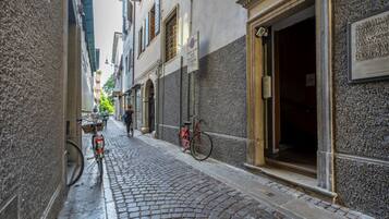 Una strada acciottolata fiancheggiata da edifici, una bicicletta e una persona che cammina.