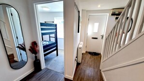A hallway with a wooden floor, a white door, a blue chair, and a radiator. - Convenient located. Bright, Spacious , Amazing View Of St Michaels Mount and Sea (Marazion)