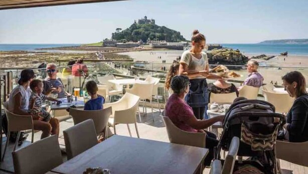 A restaurant with outdoor seating overlooking a beach and a castle. - Convenient located. Bright, Spacious , Amazing View Of St Michaels Mount and Sea (Marazion)