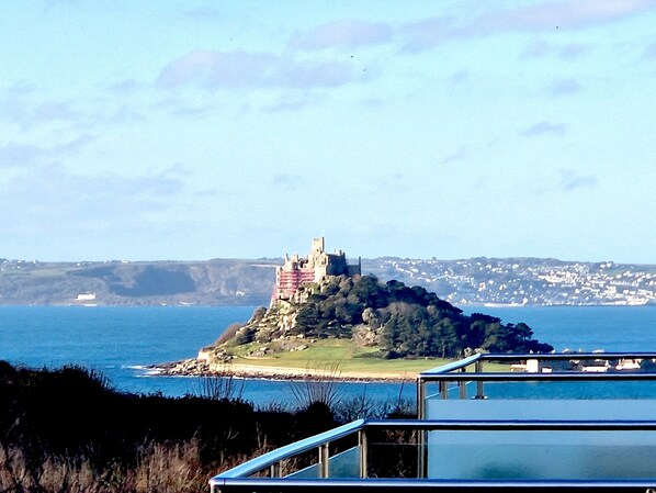 Une vue côtière avec un château perché sur une colline, dominant la mer.