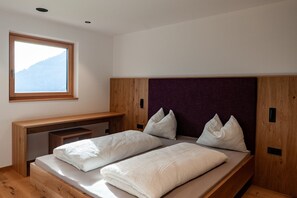 Um quarto com uma cama, uma janela e uma escrivaninha de madeira.