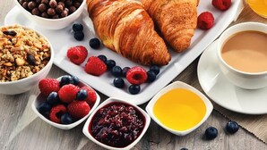 Ein Frühstückstisch mit Croissants, Beeren, Granola und einer Kaffeetasse.
