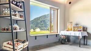 Ein Zimmer mit großem Fenster, Holzregalen mit Flaschen, einem Tisch mit Einmachgläsern und einer Topfpflanze.