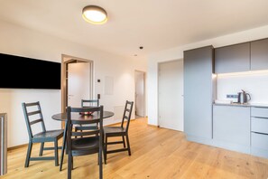 Une cuisine moderne avec des meubles de couleur grise, une table de salle à manger ronde entourée de quatre chaises et un luminaire au plafond.