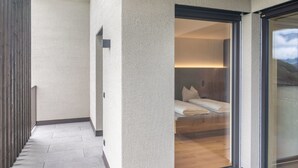 A modern hotel room with a large sliding glass door, a bed with white linens, and a wooden floor. - Apartment Hofer Hof ZIEL with Mountain View, Wi-Fi & Terrace (Algund)
