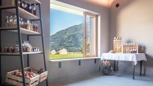 A room with a large window, wooden shelves with jars, a table with a white tablecloth, and a potted plant. - Apartment Hofer Hof ZIEL with Mountain View, Wi-Fi & Terrace (Algund)