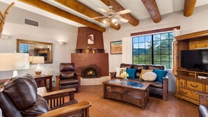 A living room with a fireplace, leather furniture, a television, and a large window. - Cereus Vista- Outstanding Views (Tucson)