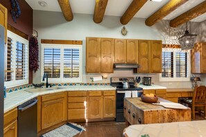 A kitchen with wooden cabinets, a stove, and a sink. - Cereus Vista- Outstanding Views (Tucson)