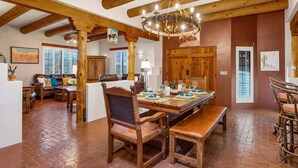 A spacious room with a wooden dining table set for six, a large wooden chair, and a chandelier. - Cereus Vista- Outstanding Views (Tucson)