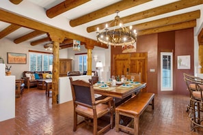 A spacious room with a wooden dining table set for six, a large wooden chair, and a chandelier. - Cereus Vista- Outstanding Views (Tucson)