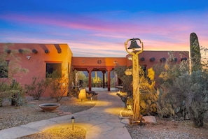 A desert-style building with a stone pathway leading to a covered entrance, surrounded by cacti and desert plants. - Cereus Vista- Outstanding Views (Tucson)