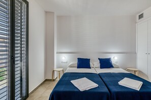 A hotel room with two beds, a balcony, and a wardrobe.
