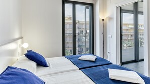 Un dormitorio moderno con dos camas, un ventanal grande y vistas de la ciudad.