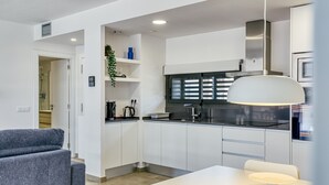 Una cocina moderna con armarios blancos, encimera negra y una lámpara colgante.
