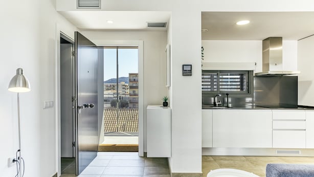 Una cocina moderna con un refrigerador de acero inoxidable, un horno empotrado y una ventana con vistas a un paisaje urbano.