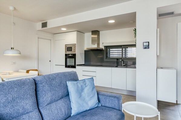 A modern kitchen with white cabinets, a built-in oven, and a microwave.