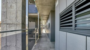 En gang med betonvægge, gelænder i glas og et metalsystem til ventilation.