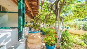 A covered outdoor area with potted plants, a large terracotta pot, and a wooden pergola structure. - Family Apartment with Sea View and Shared Pool (Corfu)