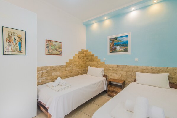 Habitación de hotel con dos camas individuales, una pared de acento de piedra y obras de arte en las paredes.