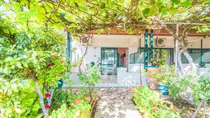 A garden pathway leading to a building with a pergola, outdoor seating, and potted plants. - Family Apartment with Sea View and Shared Pool (Corfu)