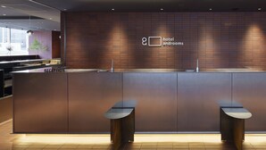 A modern hotel reception area with a reception desk, two seating areas, and a wall-mounted sign indicating hotel and rooms. - hotel androoms Sapporo Susukino (Sapporo)